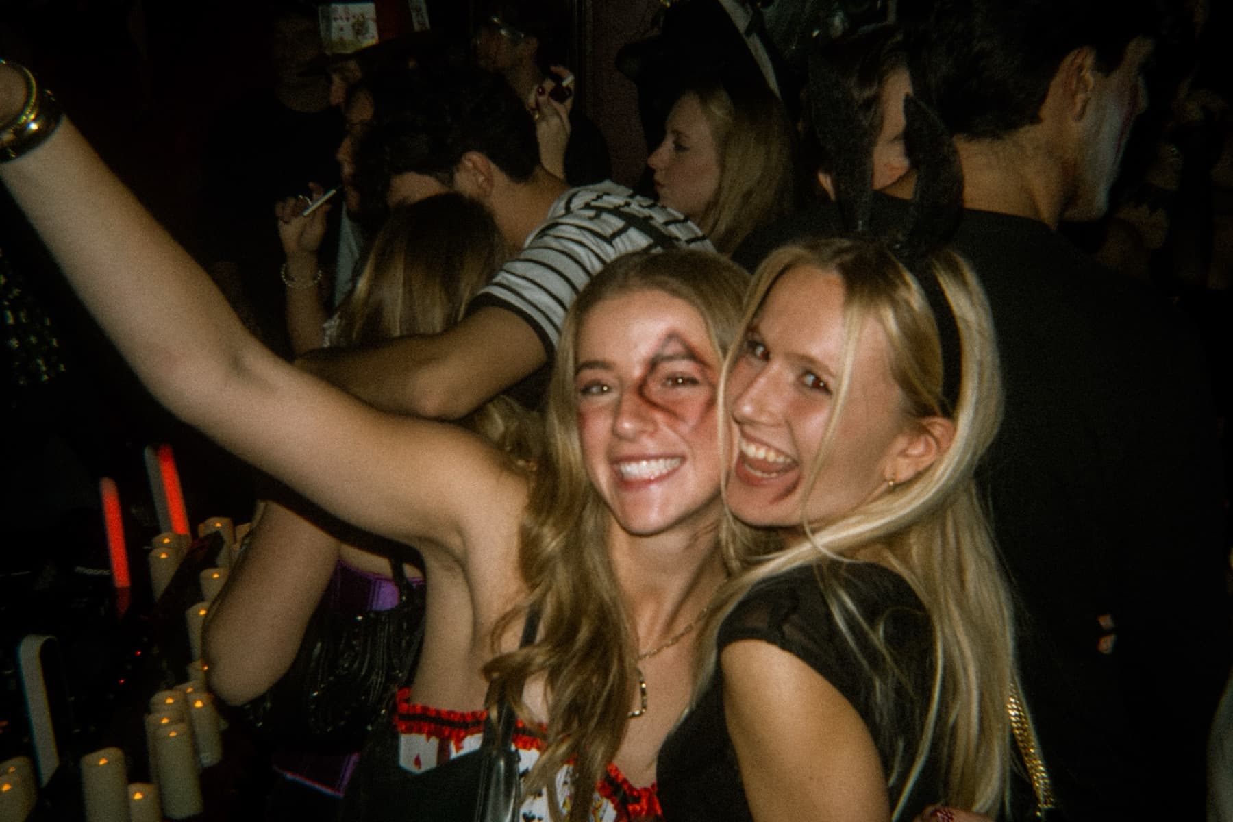 Two women with Halloween face paint laughing and posing with arms up on the dance floor