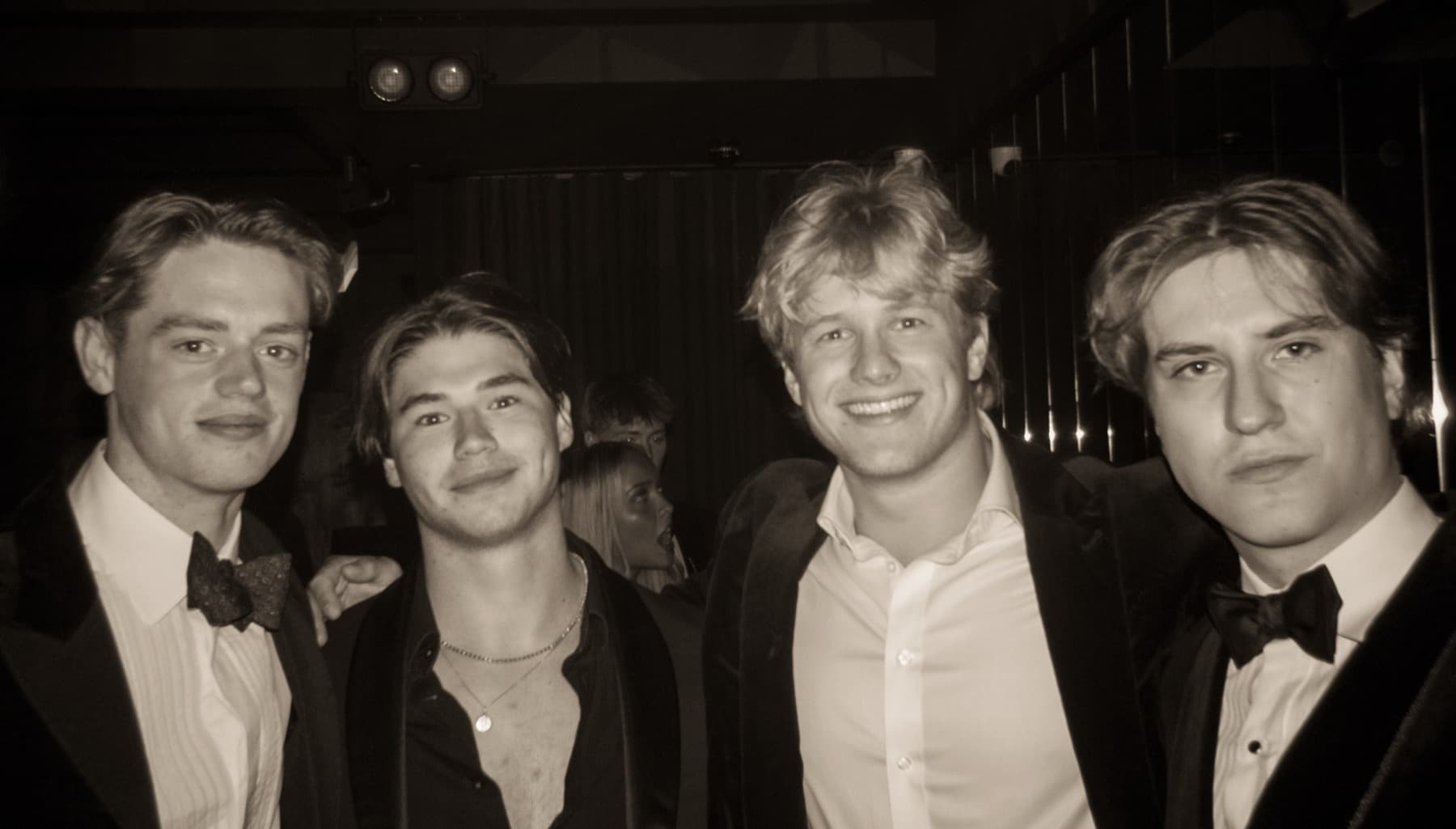 Four friends in smart evening wear posing together inside the dark club