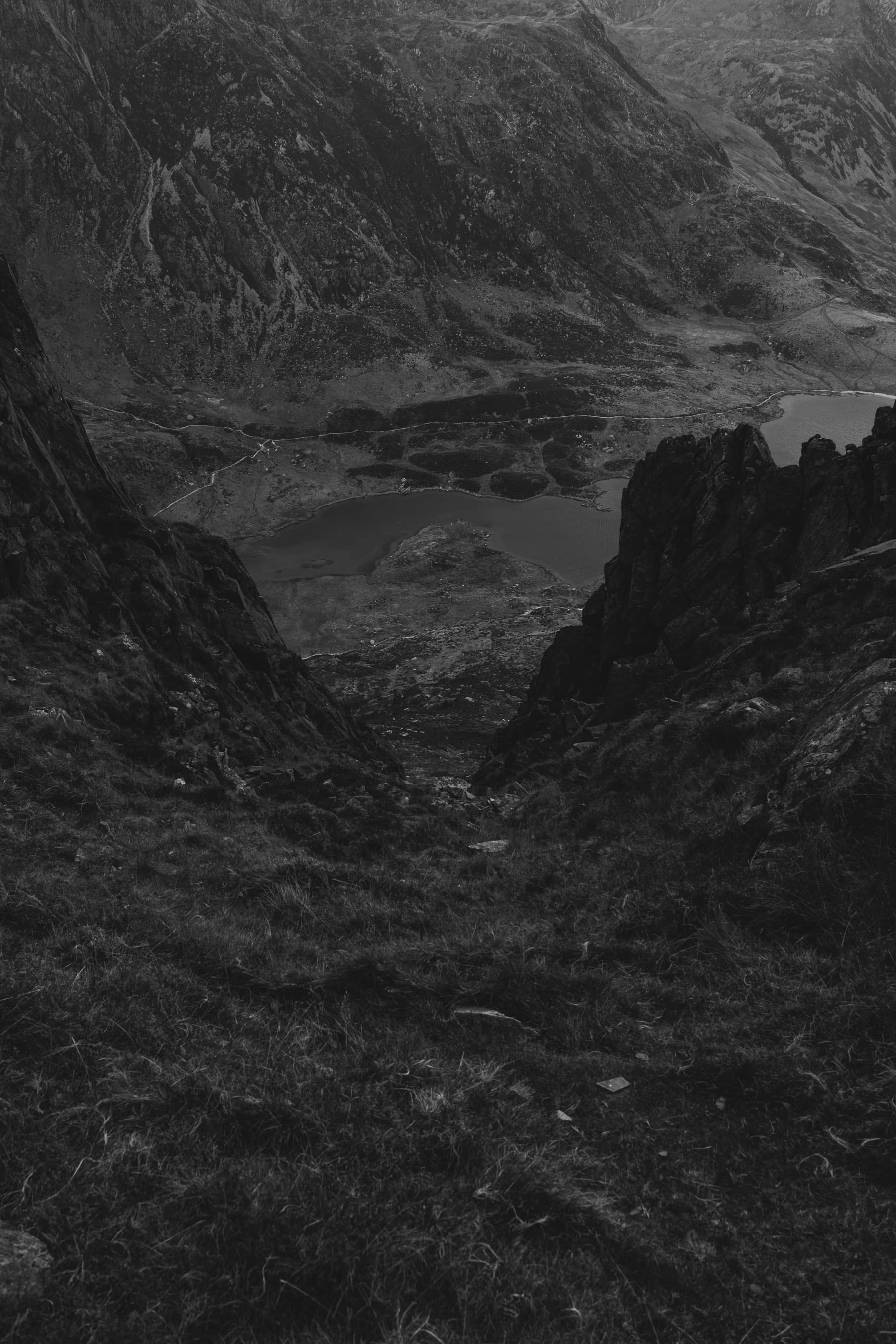 View down through rocky crags to a lake far below in a mountain cwm, shot in black and white
